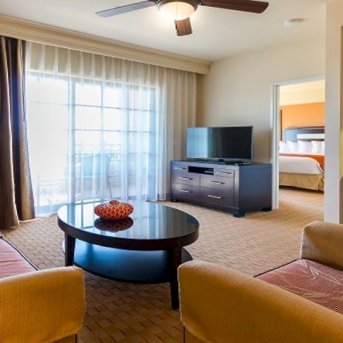 A cozy living room with a warm. blue ceiling light, two sofas facing a coffee table, a TV, and warm ambient lighting.